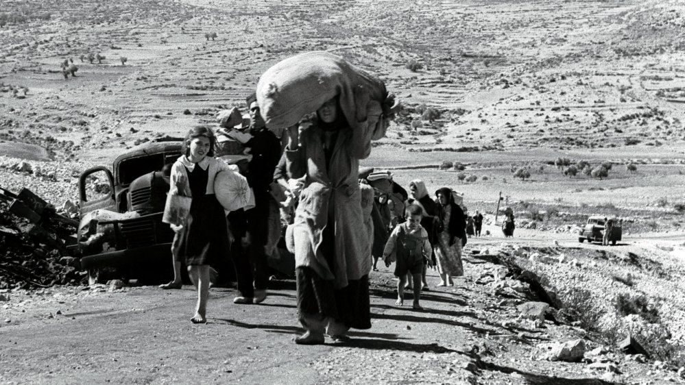 A black and white picture of people being forcefully displaced by the aggression of
the terrorist state israel during the Nakba